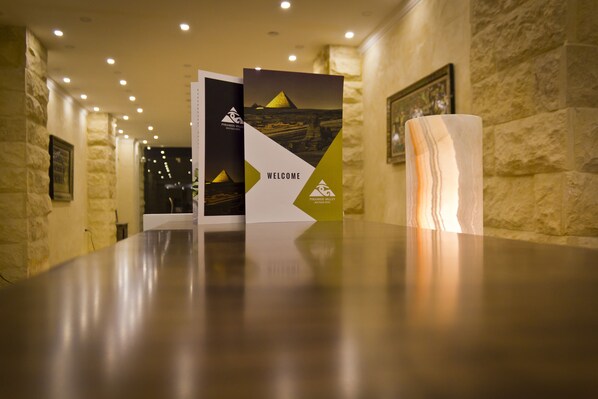 A reception area with a polished reception desk, a welcome brochure, and a marble sculpture.