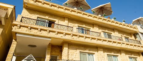 Een meerhoog gebouw met balkons, parasols en een logo dat een hotel met de naam 'Pyramids Valley' aanduidt.