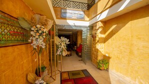 A hotel lobby with a central floral arrangement, a staircase, and a sign above the entrance. - Pyramids Valley (Giza)