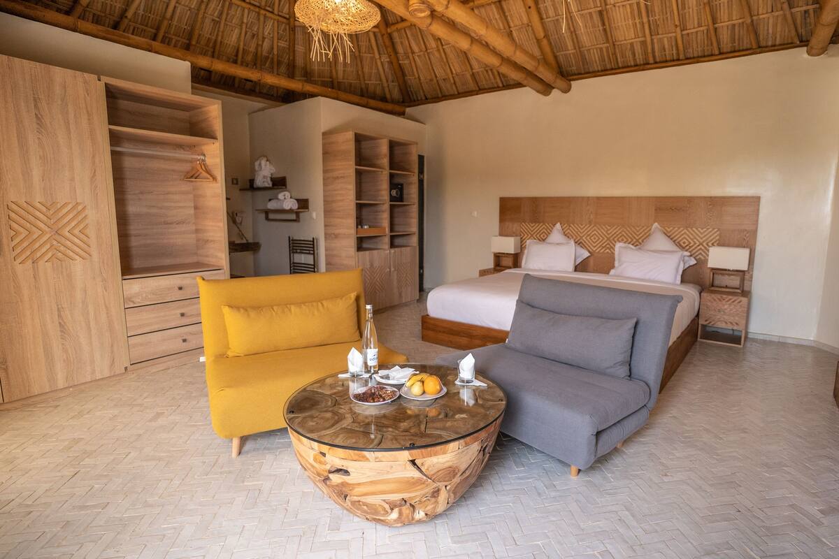 Ein Hotelzimmer mit einem Bett, einem Sofa, einem Sessel, einem runden Couchtisch und einem Kleiderschrank.