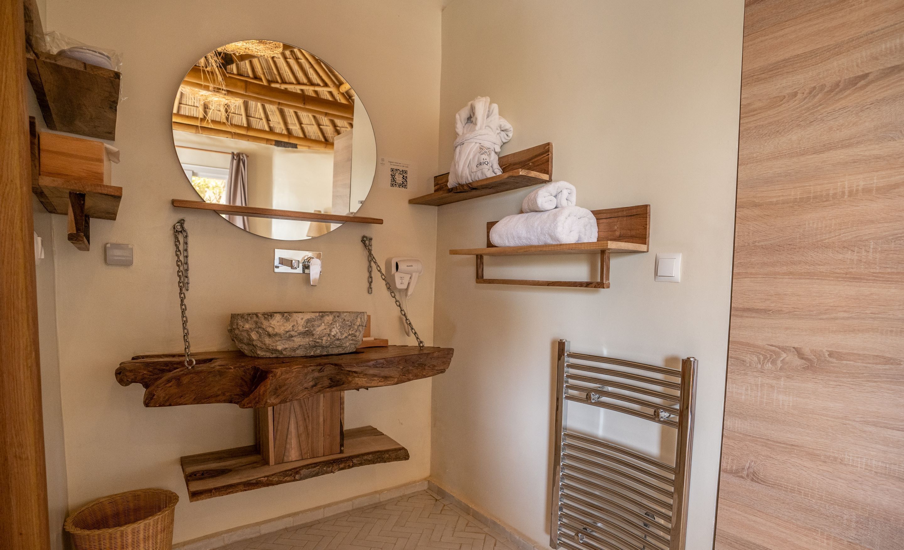 Un baño con tocador de madera, un espejo grande y repisas con toallas.
