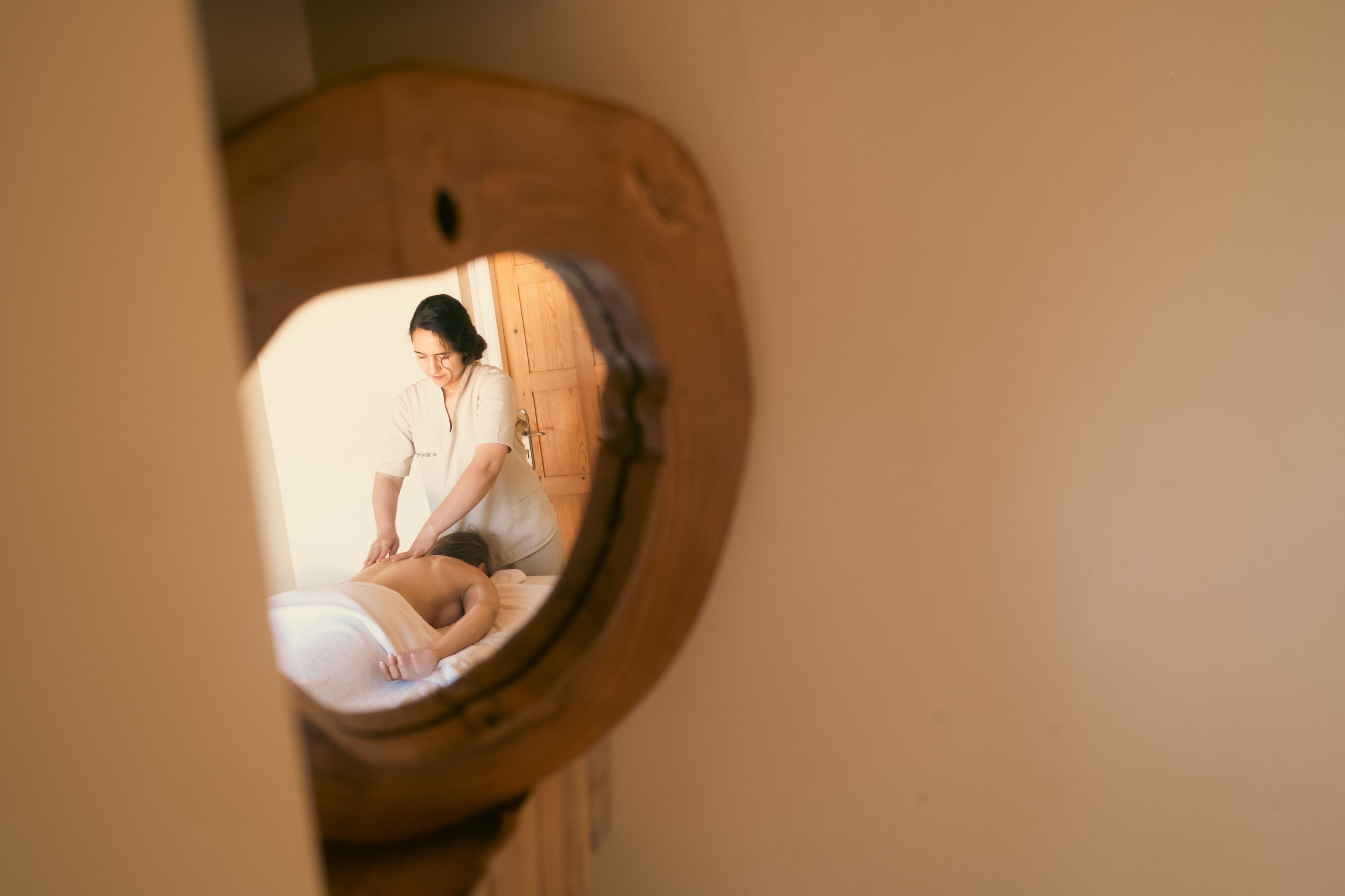 A person sitting in a wooden chair with a wooden door in the background.