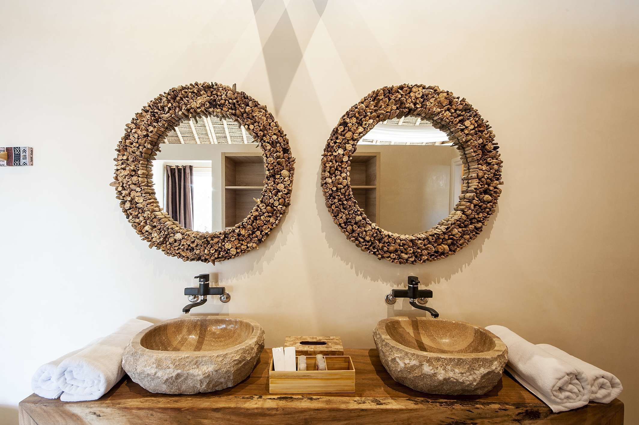 A bathroom with two stone sinks, wooden countertops, and mirrors framed with wood.