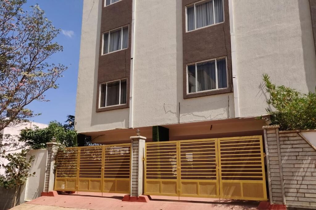 Un immeuble à plusieurs étages, doté d’une façade beige, de grandes fenêtres et d’une entrée fermée par un portail.