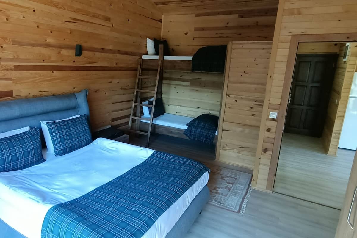 Un dormitorio de cabaña de madera con literas, una mesita de noche y un armario.