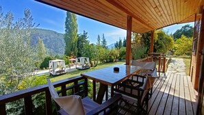 Eine Holzdar Terrasse mit Sitzgelegenheiten und Blick auf eine Berglandschaft.