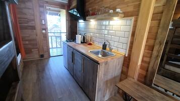 A compact kitchen with wooden cabinetry, a stainless steel sink, and a tiled backsplash.