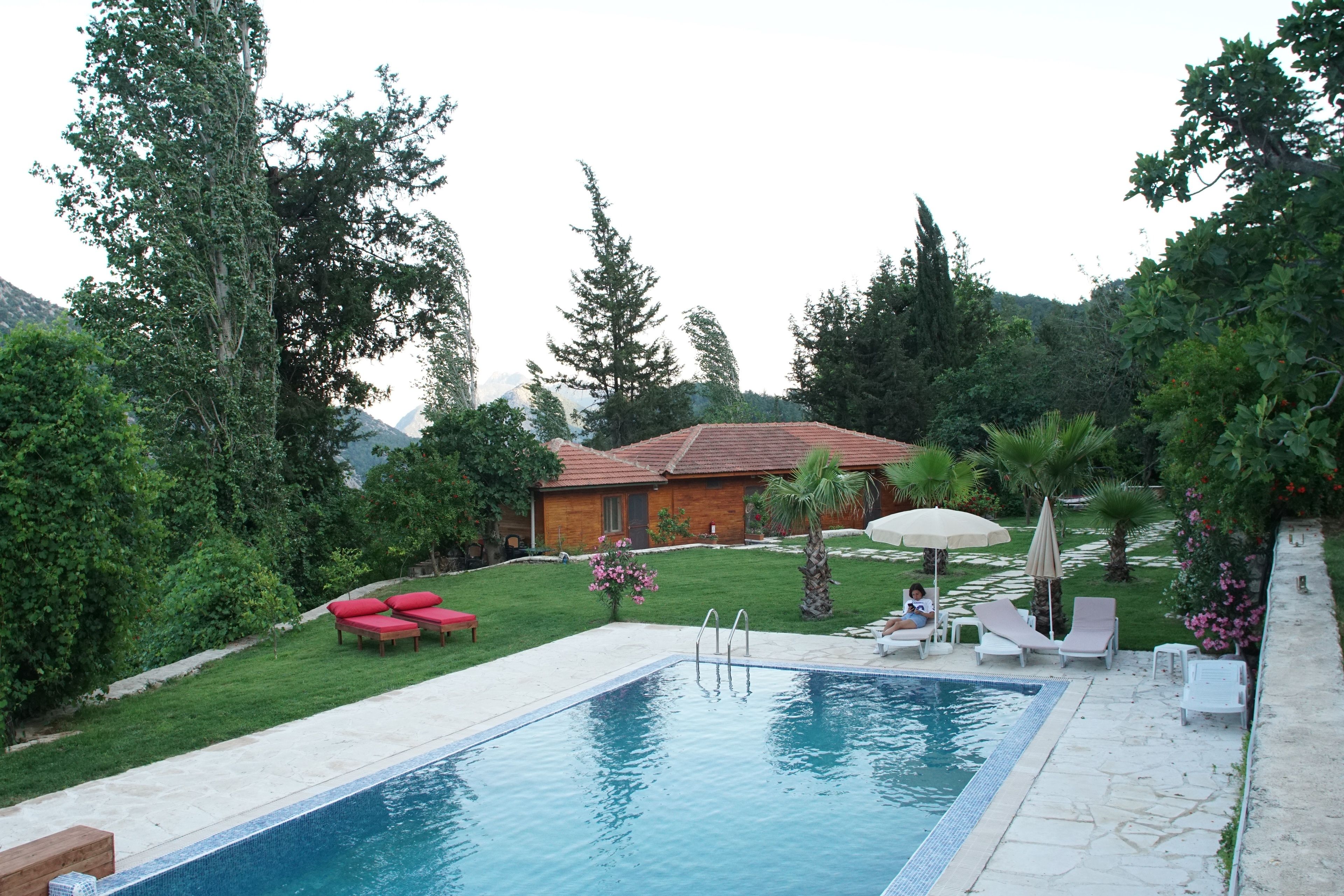 A swimming pool with lounge chairs and a small house in the background.