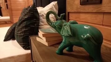 A wooden dresser with a green elephant figurine, a plaid pillow, and a stack of books.