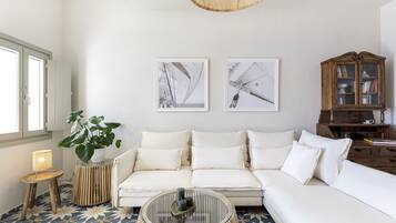 Un salon moderne avec un canapé blanc, une table basse en verre et un meuble en bois.