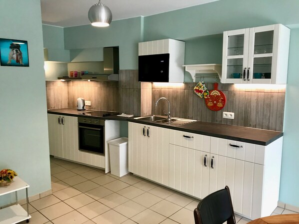 A modern kitchen with white cabinets, a black countertop, and a stainless steel range hood.