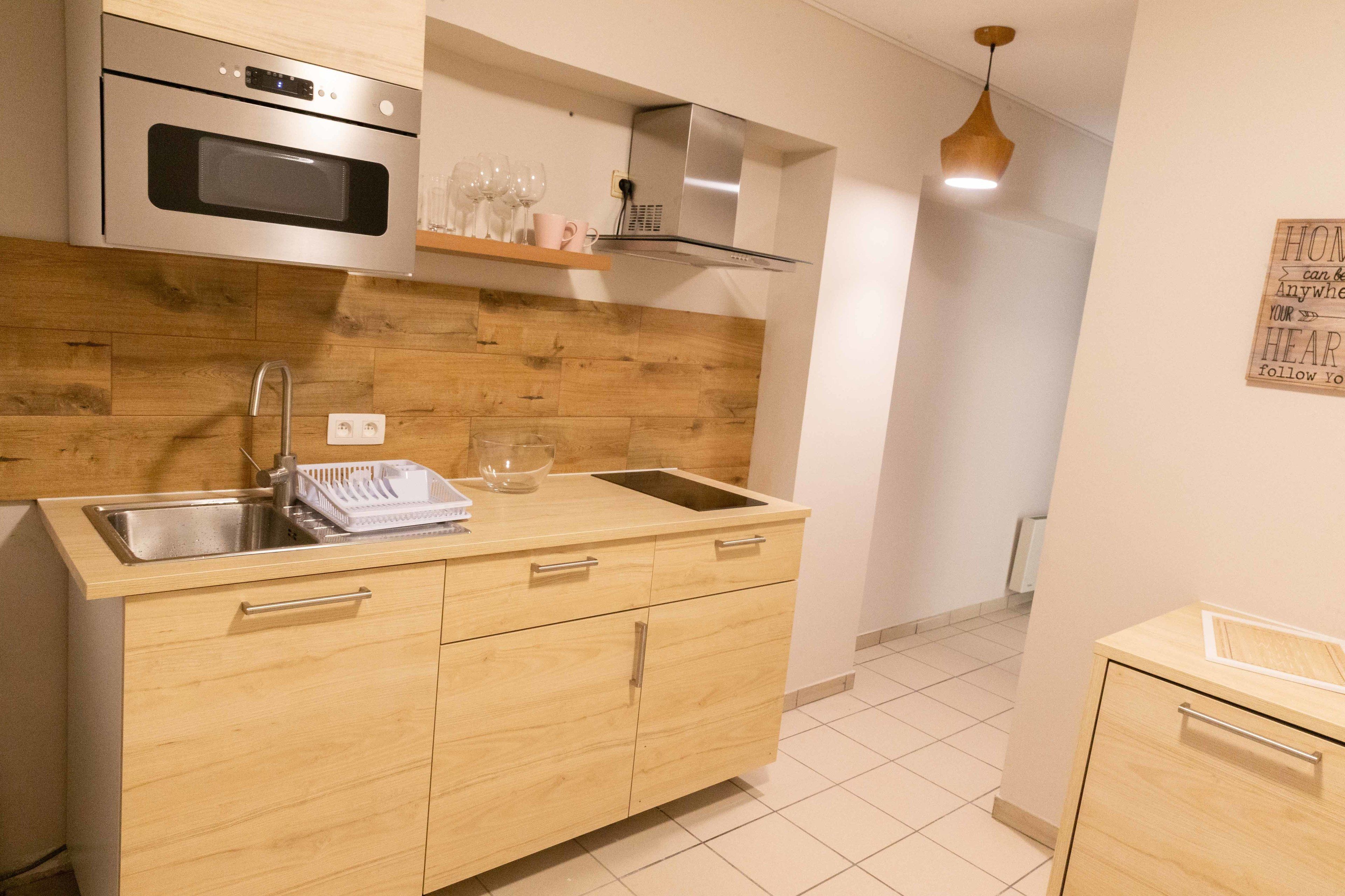 Een moderne keuken met houten kastjes, roestvrijstalen apparatuur en een inbouwoven.