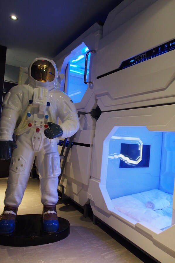 Une chambre sur le thème de l’espace, avec un lit et une statue d’astronaute à taille réelle.