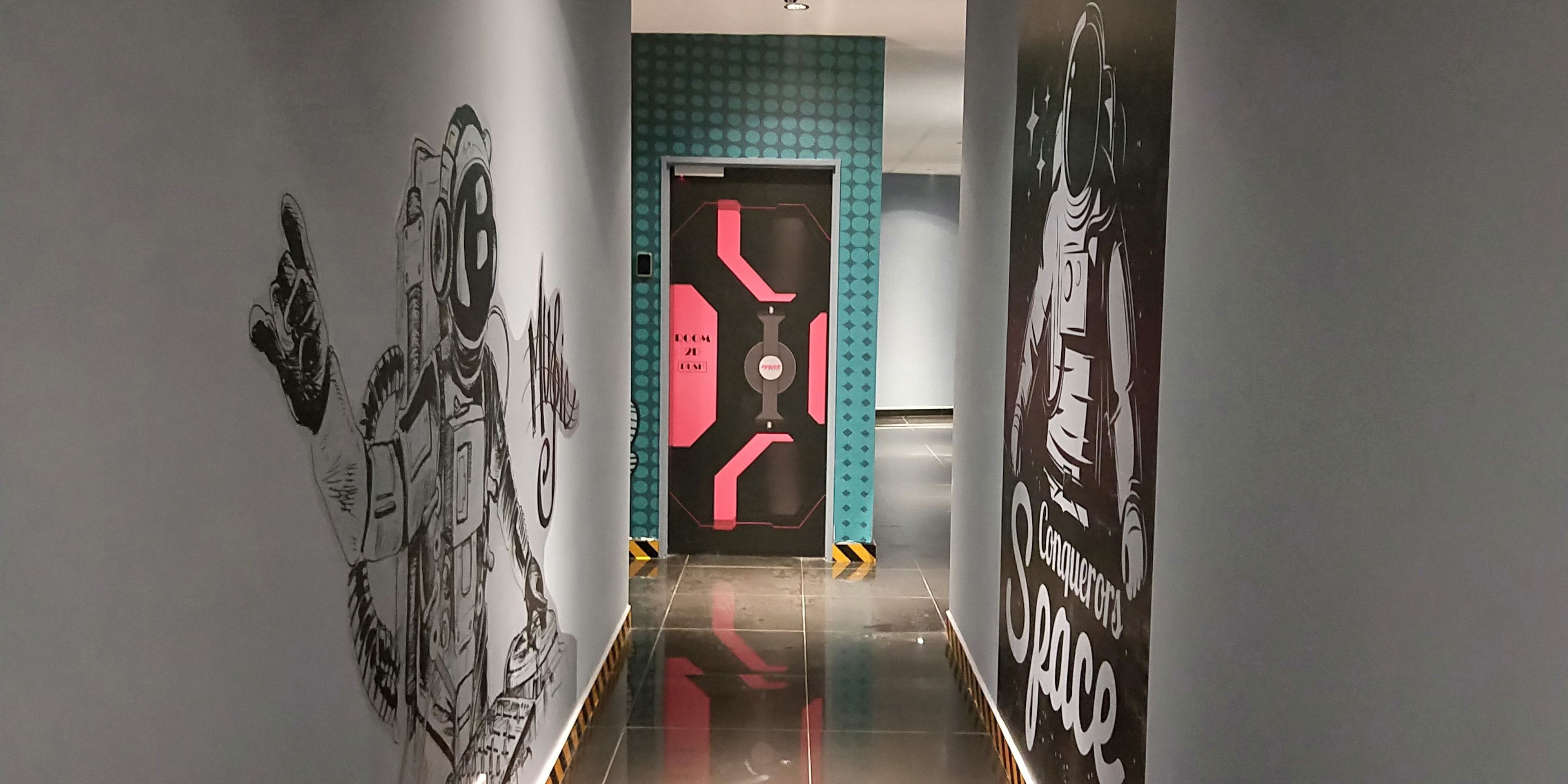 A hallway with a modern design, featuring a door with a geometric pattern and a wall with a space-themed mural.