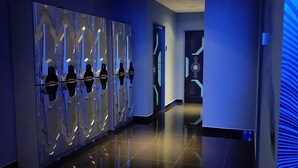 A modern hallway with a reflective wall and a blue light pattern on the right. - Space Hotel (Kuala Lumpur)