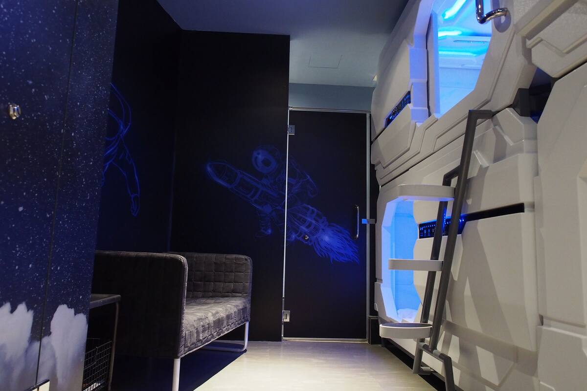 A room with a bed, a desk, and a wall-mounted projector displaying a blue image.