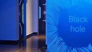 A hallway with a blue-lit wall and a sign reading "Black hole". - Space Hotel (Kuala Lumpur)