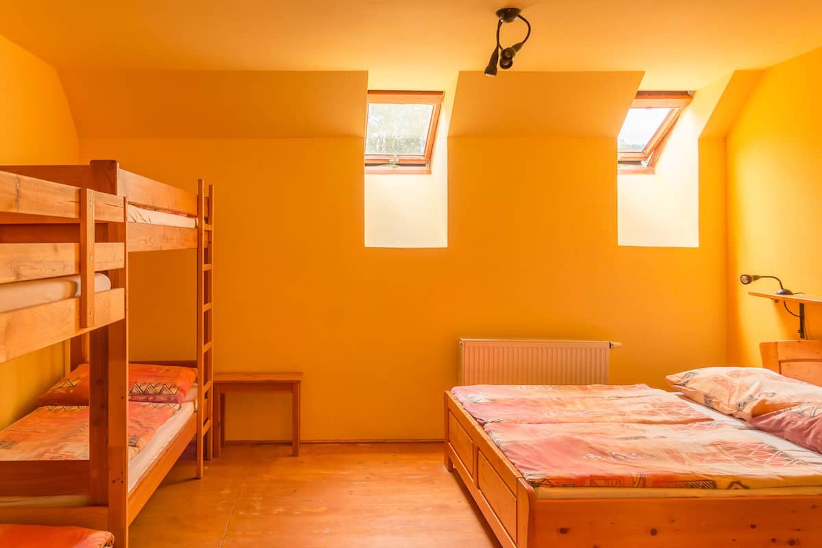 A dormitory room with bunk beds, a radiator, and skylights.