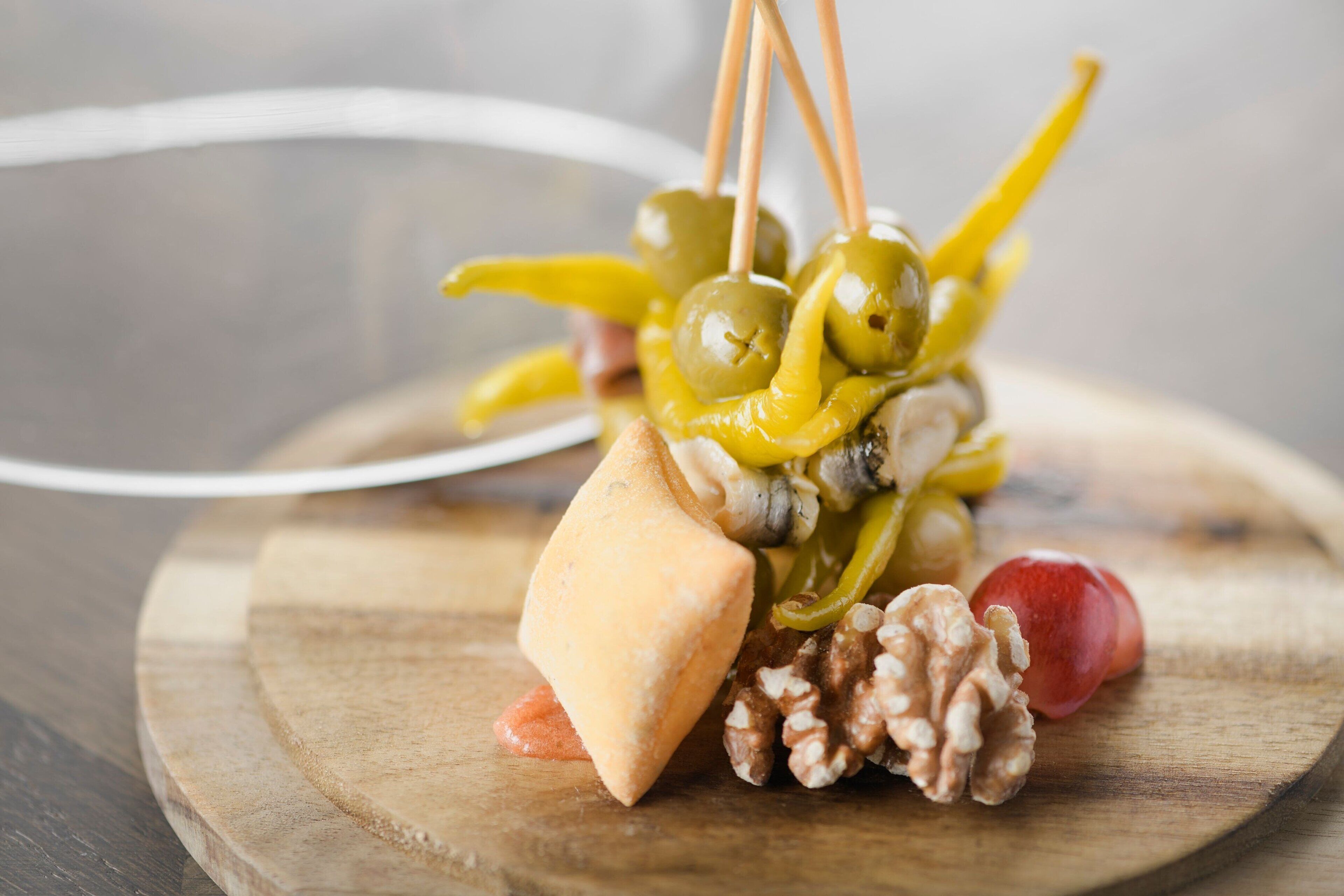 A wooden board with a pastry, grapes, and a walnut.