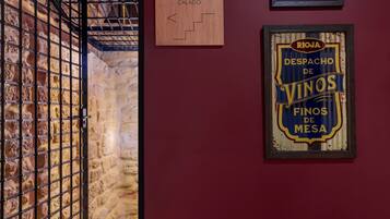 A stone wall with a metal gate, a wooden sign labeled "CALADO," and a framed sign with "RIOJA DESPACHO DE VINOS FINOS DE MESA."