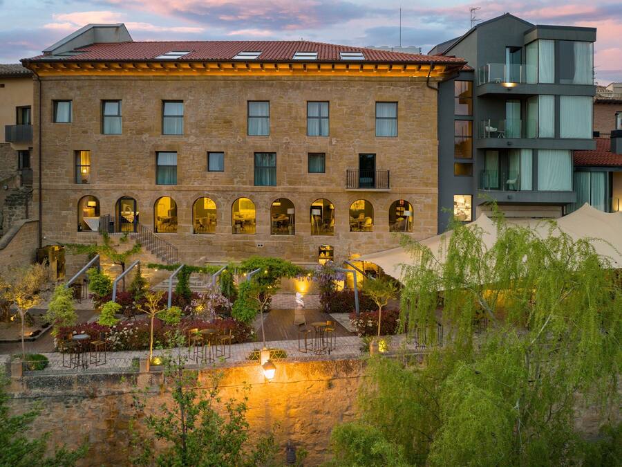 A historic building with multiple floors, arched windows, and a courtyard with outdoor seating.