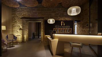 Un vestíbulo de hotel con pared de piedra, un mostrador de recepción e iluminación moderna.