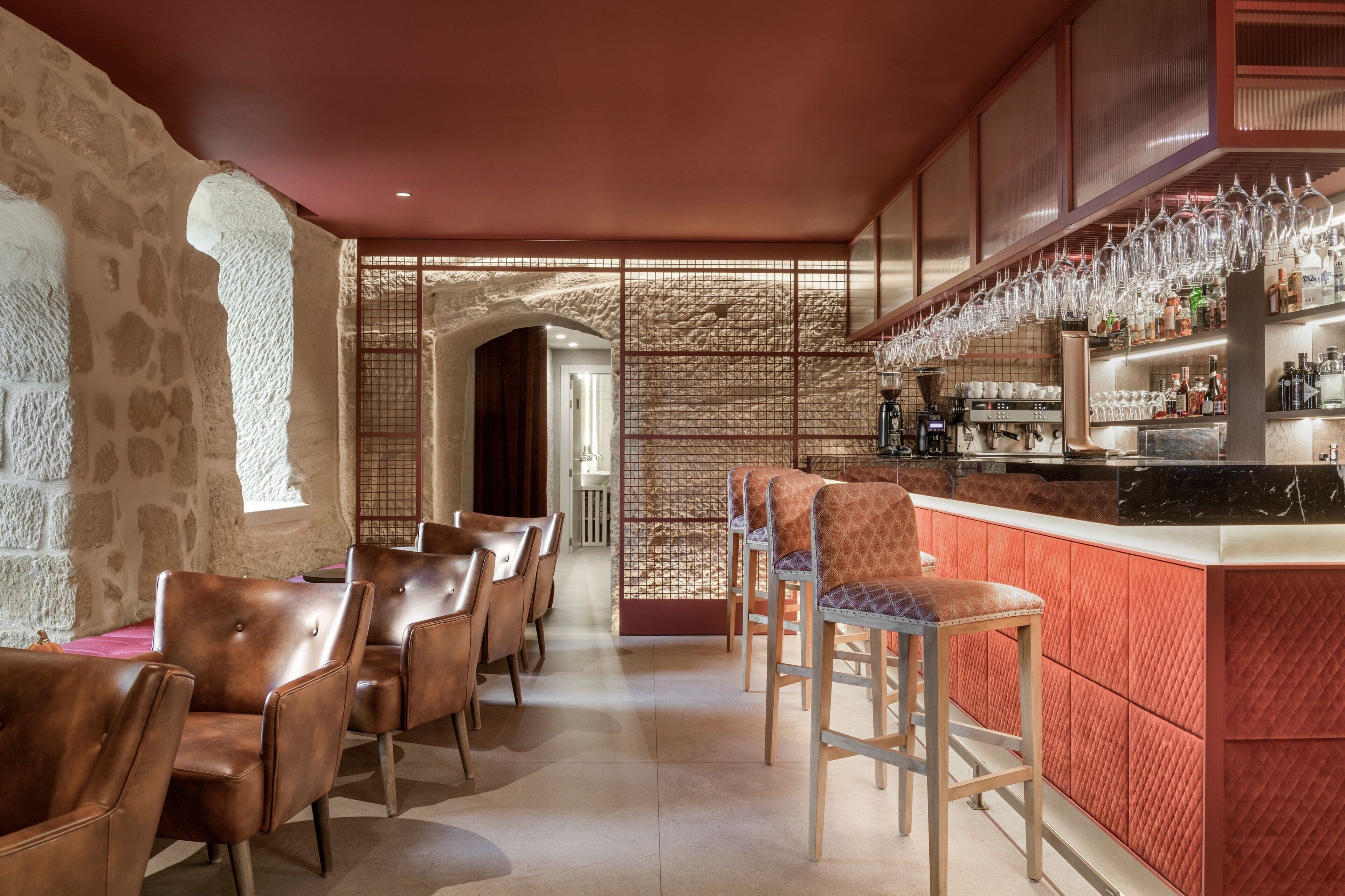Una zona de bar con taburetes, una barra con botellas y una pared de piedra.