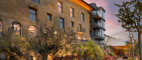 A courtyard with a large tree, outdoor seating, and a building with multiple windows and balconies.