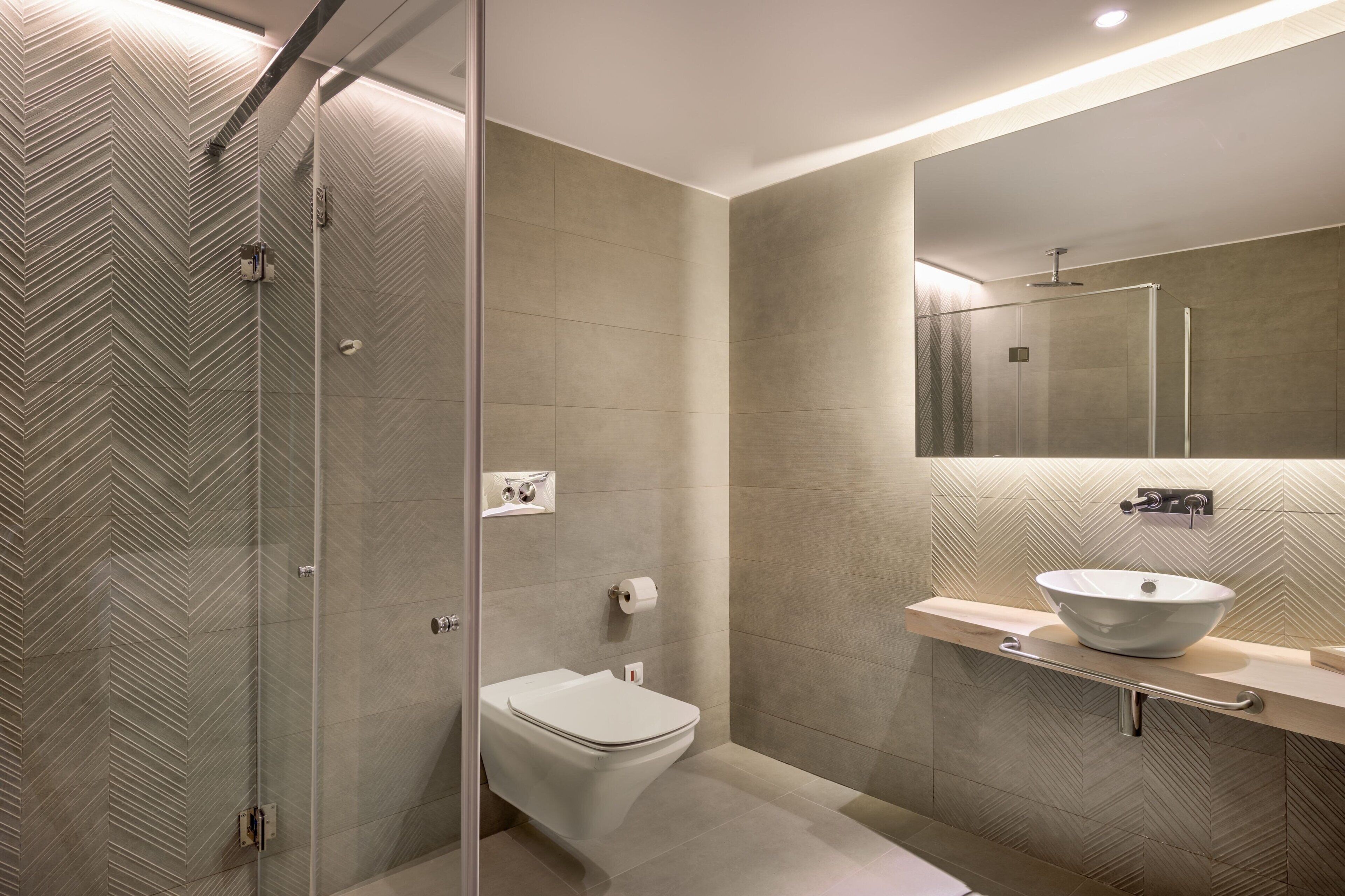 A modern bathroom with a glass shower enclosure, a white toilet, and a vessel sink on a countertop.