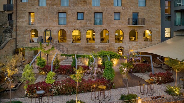 A stone building with multiple arched windows and a courtyard with outdoor seating and plants. - Palacio Tondon, Autograph Collection (Brinas)