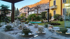 A table set for tea service with a view of a mountain and buildings in the background. - Villa Laura (Lierna)