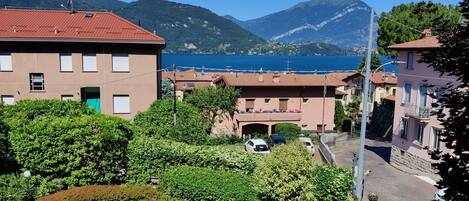 A residential area with a swimming pool, buildings with red roofs, and a view of the sea and mountains.