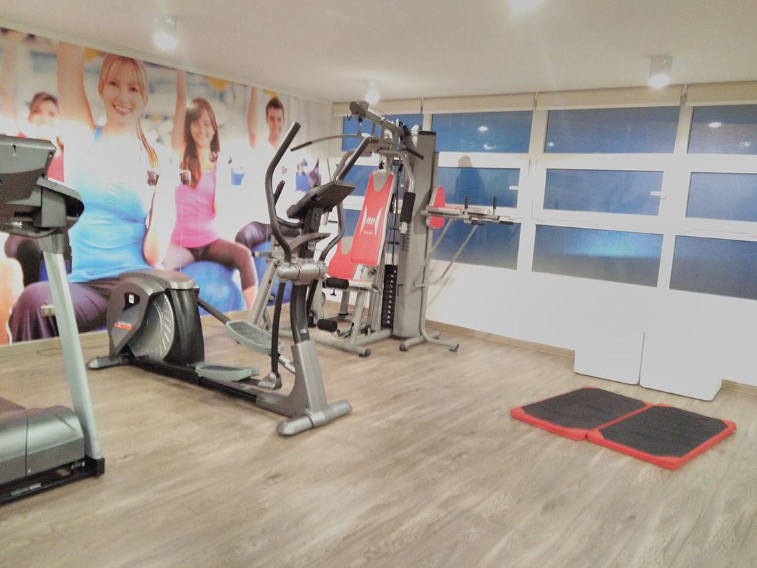 A gym with cardio machines, weight training equipment, and a mirror.