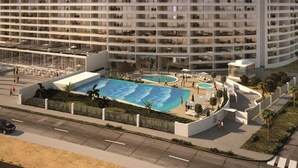 Un hotel de varios pisos con una amplia zona de piscina, mobiliario exterior y un jardín ajardinado.