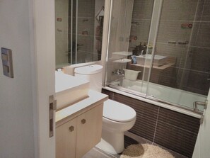 A modern bathroom with a toilet, sink, and shower area.