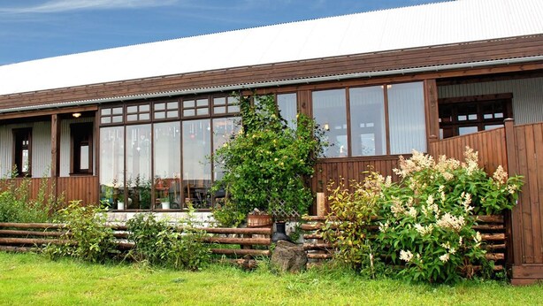 A wooden building with large windows and a covered porch. - Raven's Bed and Breakfast (Reykjanesbær)
