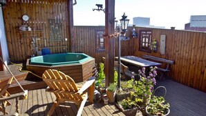 A wooden deck with a hot tub, wooden chairs, a table, and potted plants. - Raven's Bed and Breakfast (Reykjanesbær)