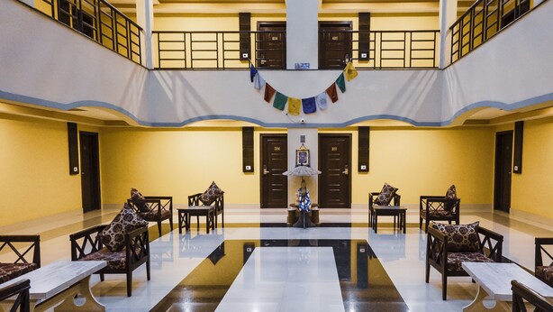 Um saguão com área de estar central, várias portas e uma bandeira decorativa.