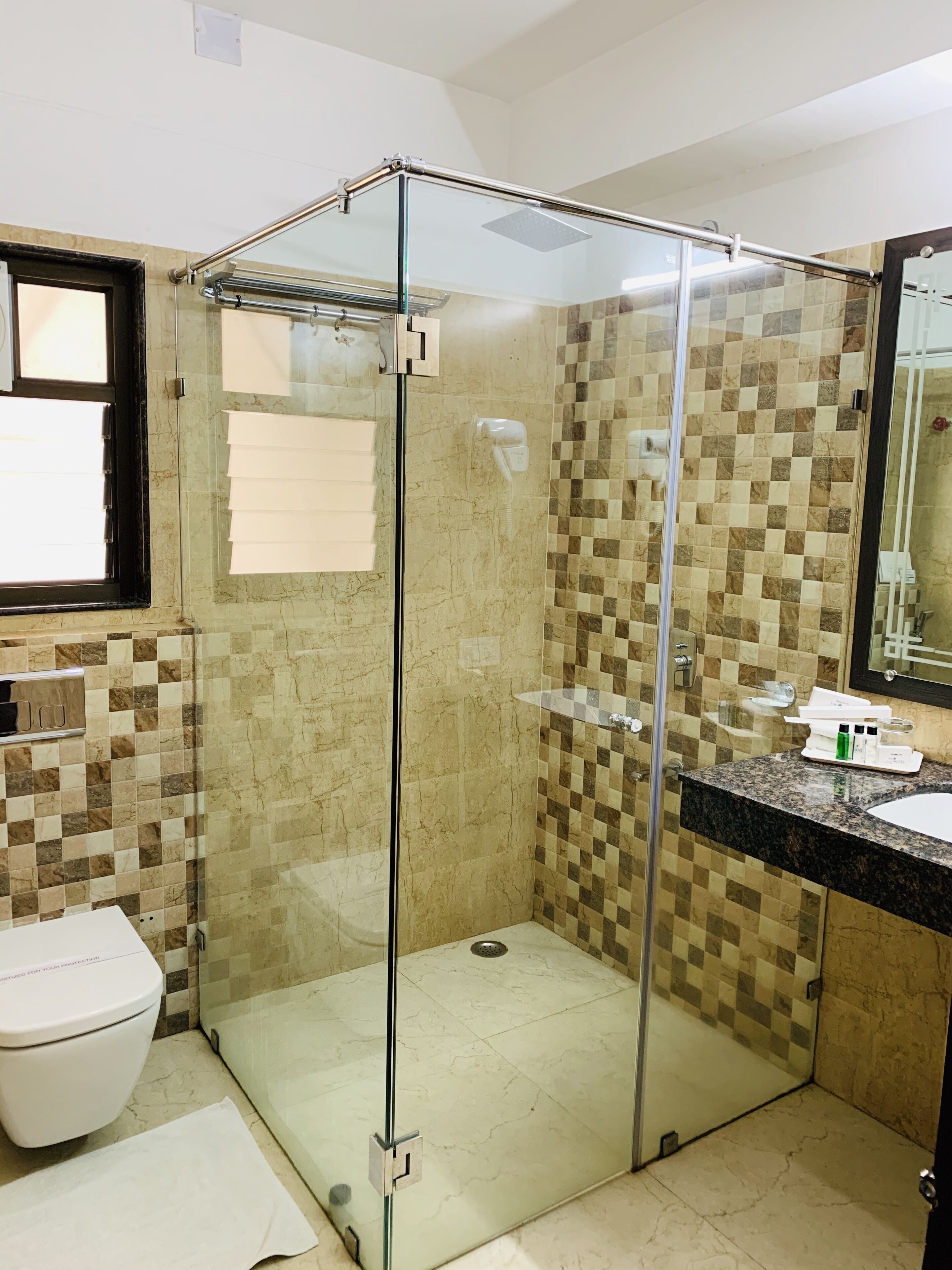 A bathroom with a glass-enclosed shower, a white toilet, and a tiled wall.