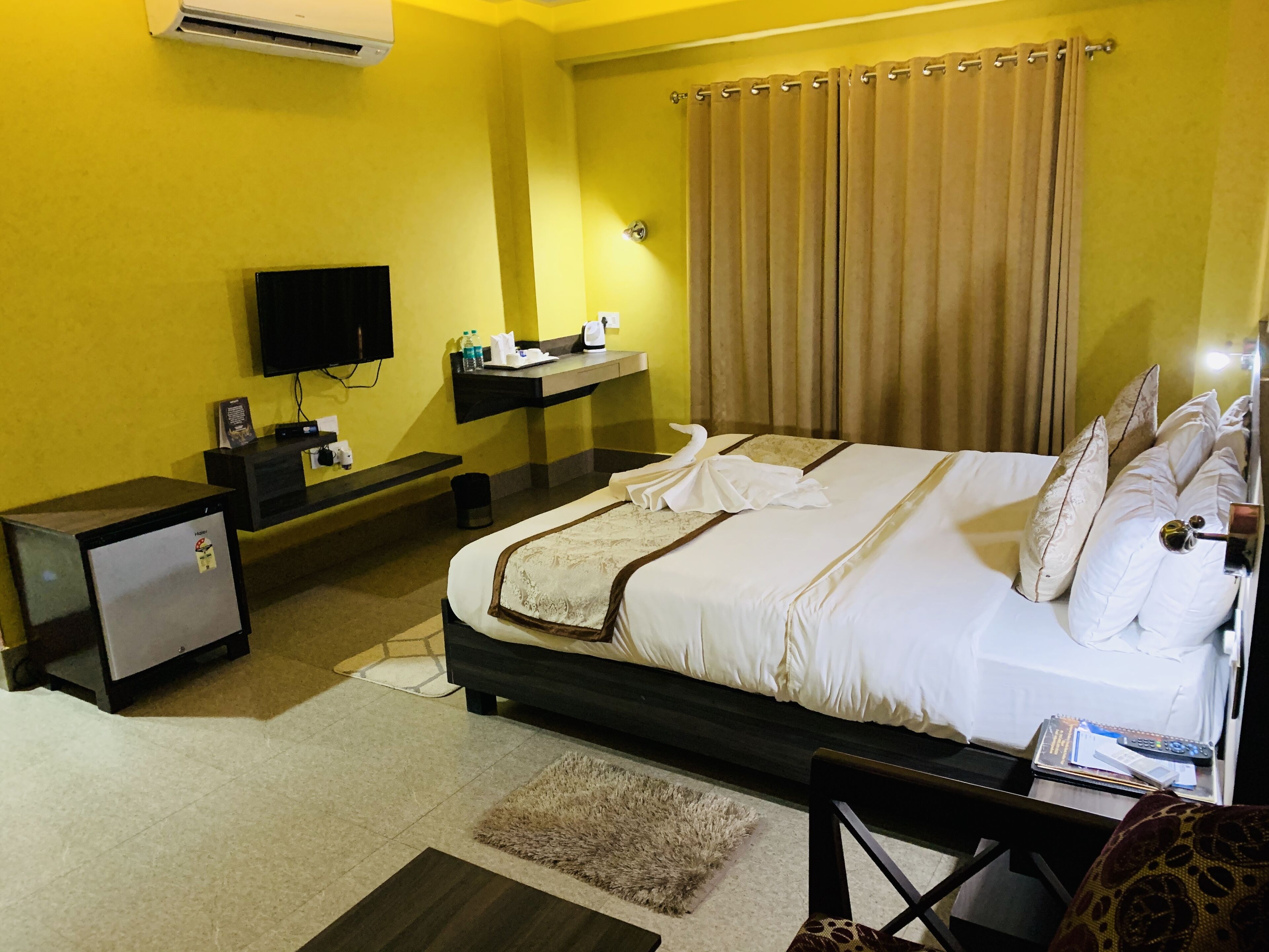 A hotel room with a bed, a desk, a television, and a minibar.