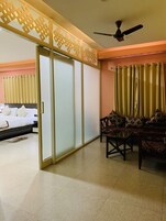 Una habitación de hotel con cama, sofá, mesa y ventilador de techo.