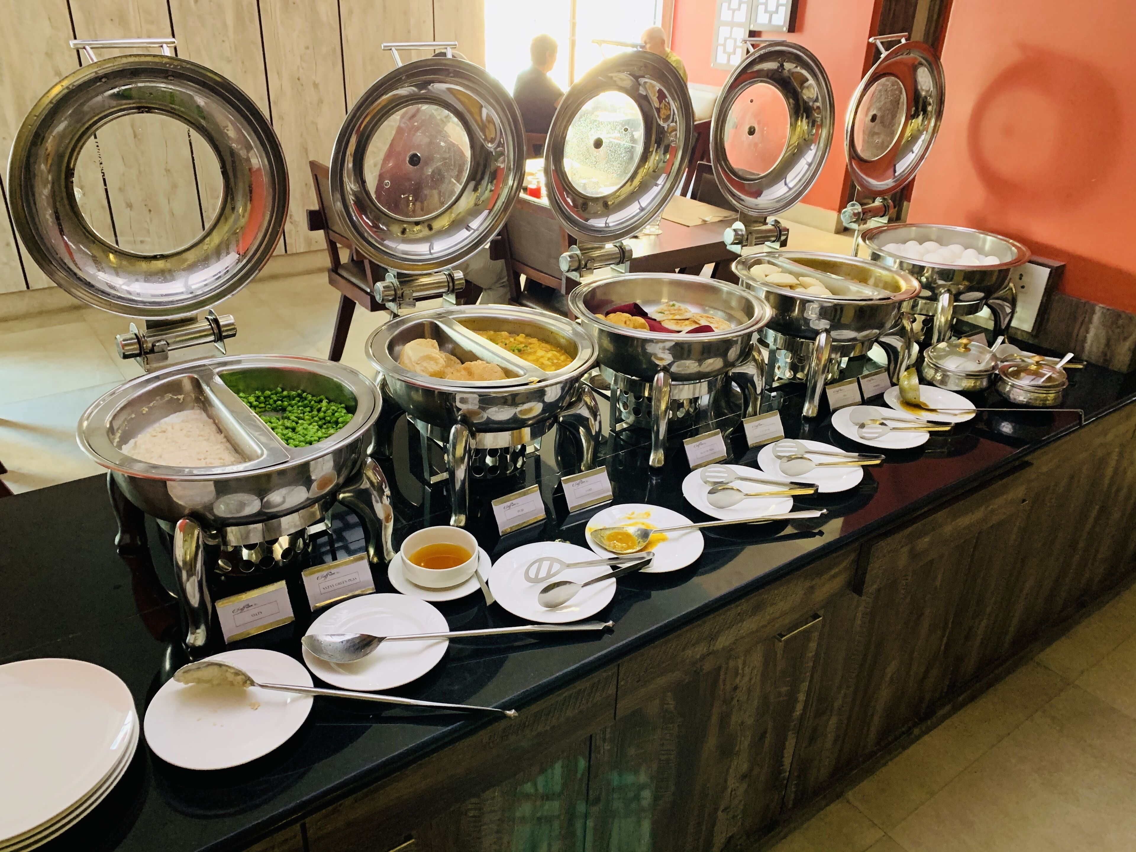 A buffet with multiple food dispensers, including options for rice, peas, and various other dishes.