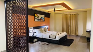 Quarto de hotel moderno com uma cama grande, um separador decorativo, um quadro na parede e um lustre.