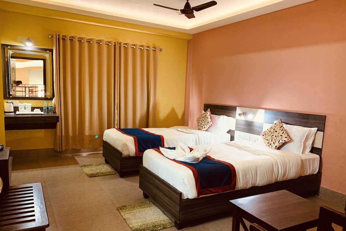 A hotel room with two beds, a desk, a chair, a mirror, and a bathroom area.