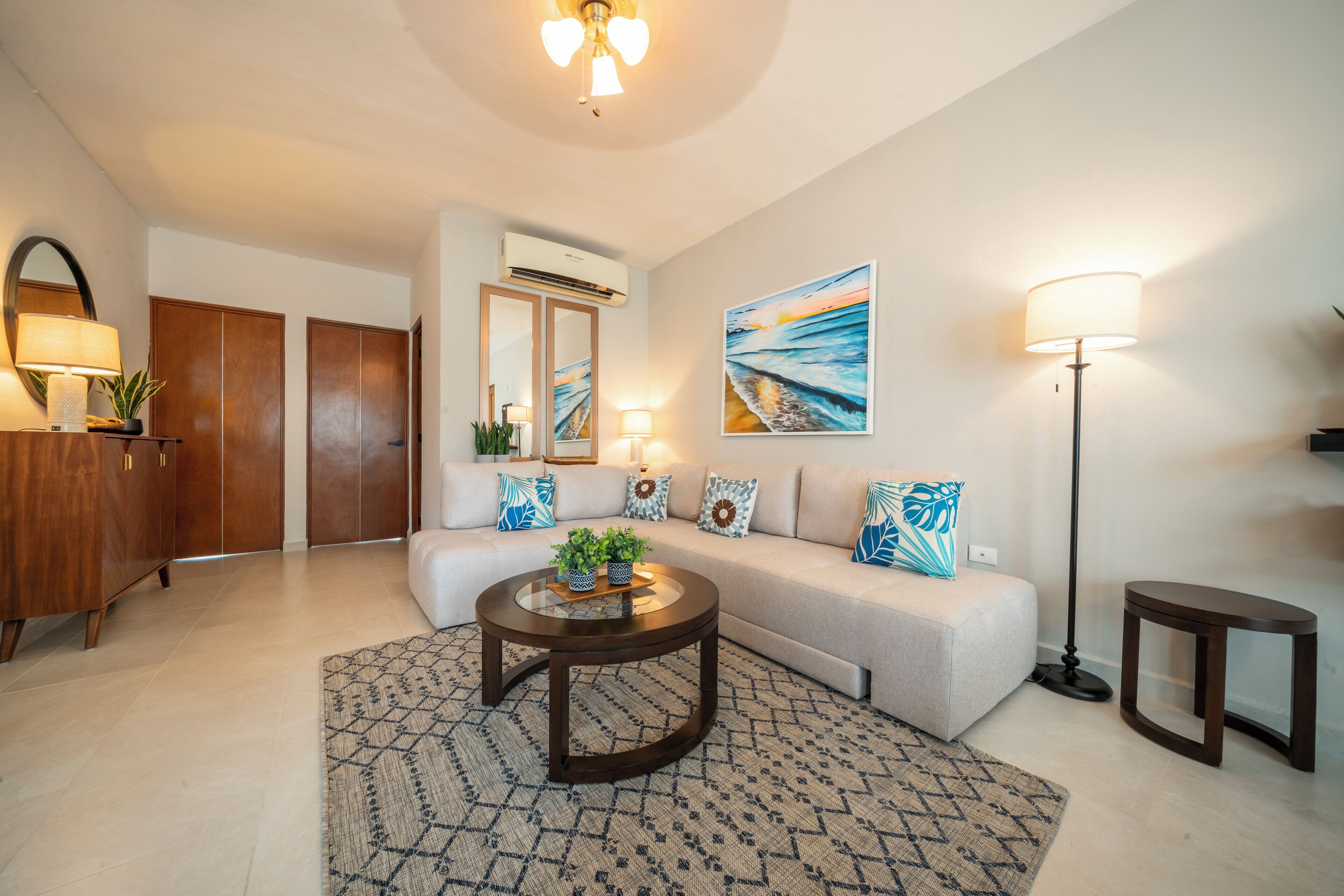 A modern living room with a sofa, a coffee table, a lamp, and a painting on the wall.