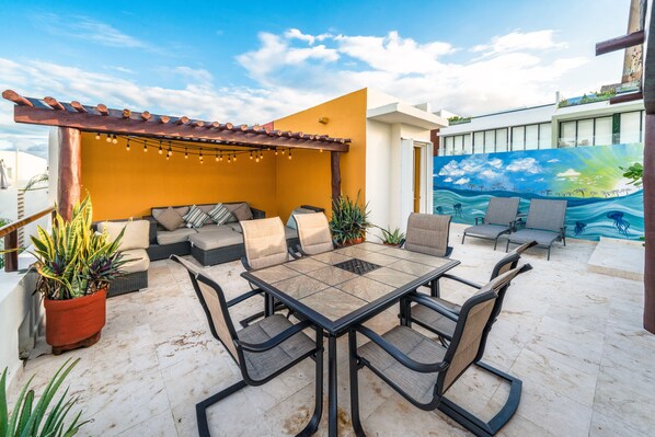 An outdoor patio with a dining table and chairs, a sofa, and potted plants.