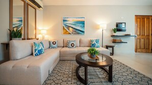 Sala de estar com sofá bege, tapete estampado e mesa de centro redonda com uma planta.