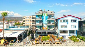A hotel with multiple floors, outdoor seating area, and a colorful mural on the building facade. - Yasemin Hotel (Fethiye)