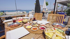 A table set with various food items and a view of the beach. - Yasemin Hotel (Fethiye)