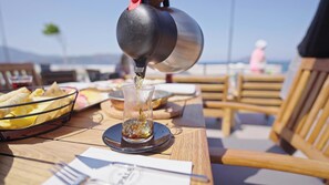 A table with a glass of drink being poured, surrounded by plates of food and a bottle. - Yasemin Hotel (Fethiye)